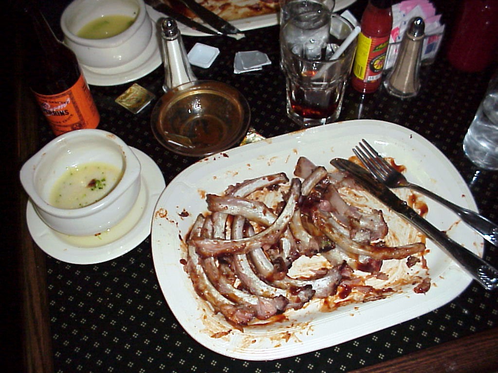 Dinner table at a restaurant showing pile of rib bones left over after completed meal